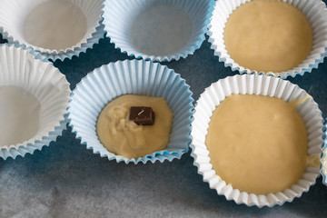 Paper mold with a piece of chocolate and dough to make muffins