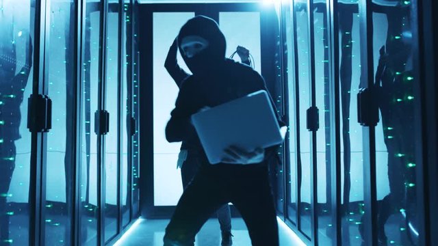 Successful cybercrime. Happy hooded computer hackers having fun in database, breaking servers and stealing information, dancing excited in server room. Data center.