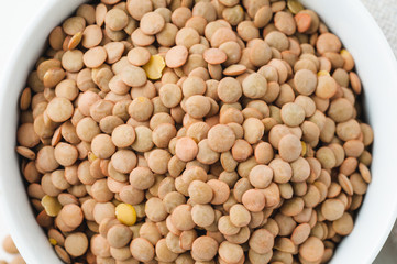 Dried green lentils on a white plaster textured background