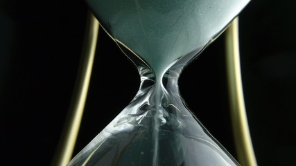 Still hourglass clock time concept. Old vintage gold metal frame green sand clock countdown on dark...