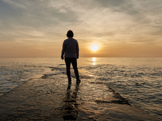 woman standing on a sea breakwater