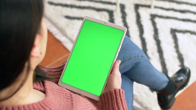 Young Ukrainian woman in modern living room hold tablet with green screen. Close up 4k commercial footage.