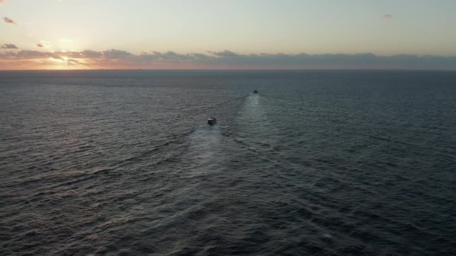 Aerial Footage Following Two Boats Out to Sea at Sunrise - Back View