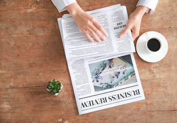 Naklejka premium Young woman reading newspaper at table