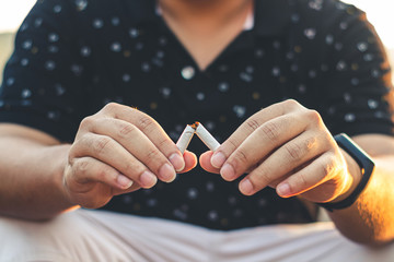 Men hand caught a burning cigarette causing smoke, concept stop smoking.