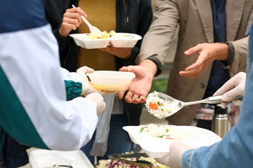 Volunteers giving food to homeless people outdoors