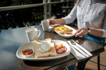 Healthy breakfast eggs and toast and tomato with woman hands touching the plates
