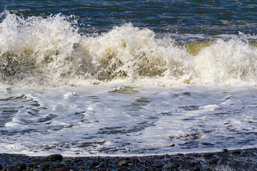 Waves break on the shore with white foam