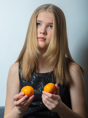 Sad girl holding tangerines in her 