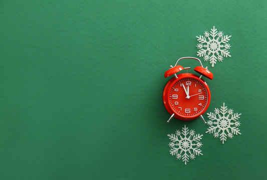 Alarm clock with snowflakes on color background