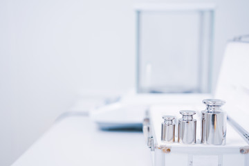 Selective focus of stainless steel calibration weight for the analytical balance calibration test, concept of quality control laboratory in pharmaceutical industry.