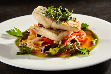 Pollock fish fillet with vegetables on white plate