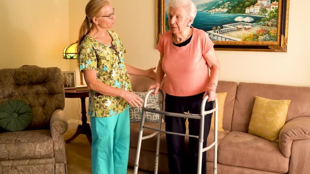 Closeup Of Home Healthcare Nurse Helps Elderly Woman Get Up From Couch And Use A Walker.