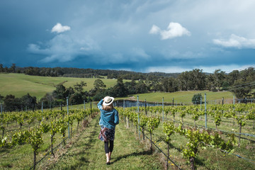 Young female walking in the vineyards in Tasmania, wearing hat and skirt, fashionable