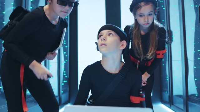 Young cute team of prodigy kids programming in server room. Spy children using a laptop coding malware programs to steal information cooperating on special secret mission.