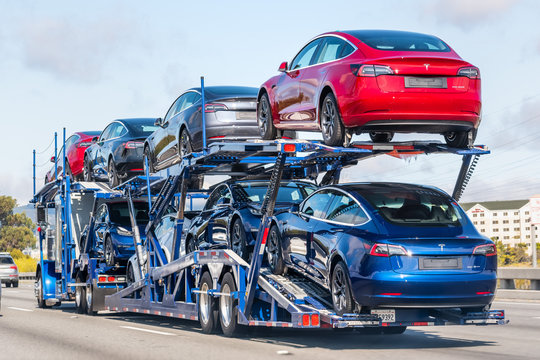 Aug 10, 2019 Burlingame / CA / USA - Car transporter carries Tesla Model 3 new vehicles on a freeway in San Francisco bay area, back view of the trailer;