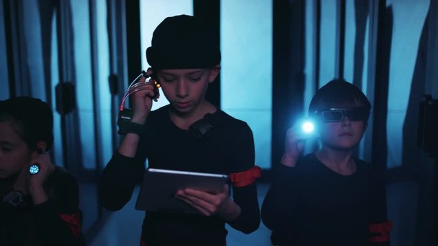 Spy kids. Young team of computer hackers breaking into server room, walking inside using flashlight and spy gadgets on secret database operation.