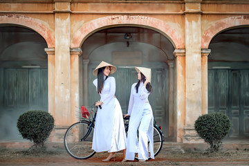 Two beautiful women in Vietnam's national costume Riding a bicycle to see ancient buildings.