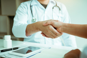Doctor shaking hands with older patient in the clinic room.