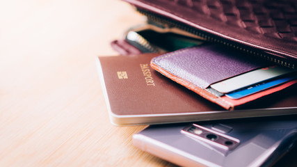 Closeup of traveler's stuffs in female purse who just arrived in Japan, wads of 10000 yen banknotes, foreigner passport, smartphone, credit and debit cards. Female solo travel, Business trip, Tourist.