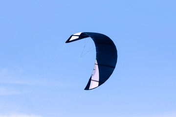 Dark blue kiteboarding kite against blue sky