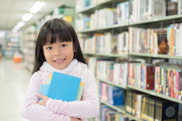 child girl holding a stack of books in the library