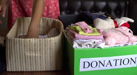 Woman Putting Clothes Inside Donation Box. Children's clothes and toys for Christmas charity