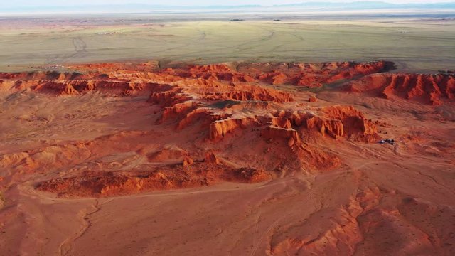 Aerial around view of the Bayanzag flaming cliffs at sunset in Mongolia, found in the Gobi Desert, 4k