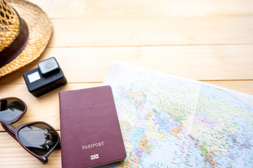 Passport with a map on wooden background.Travel planning.Top view of traveler accessories with a hat, camera, watch on world map.Preparation for travel.Traveling Journey Vacation Holiday concept.