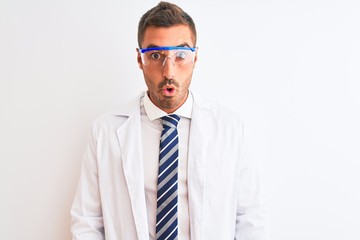 Young handsome scientist man wearing safety glasses over isolated background afraid and shocked with surprise expression, fear and excited face.