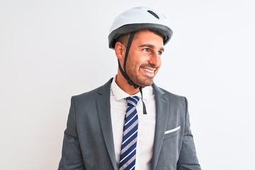 Young handsome business man wearing suit and tie and bike helmet over isolated background looking away to side with smile on face, natural expression. Laughing confident.