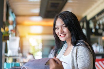 Beautiful woman in coffee cafe reading a book with relaxing