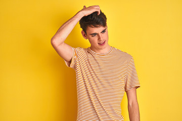 Teenager boy wearing yellow t-shirt over isolated background confuse and wonder about question. Uncertain with doubt, thinking with hand on head. Pensive concept. - obrazy, fototapety, plakaty