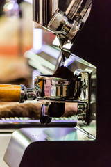 Espresso machine grinding roasted coffee bean into tamper. .