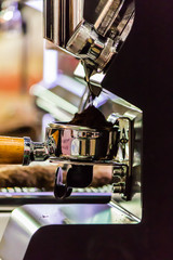 Espresso machine grinding roasted coffee bean into tamper. .