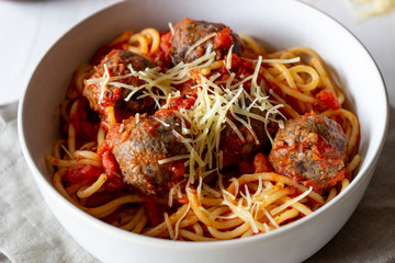 Pasta with meatballs and tomato sauce on a wooden background.