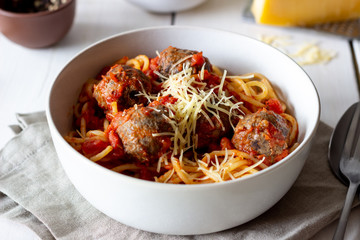 Pasta with meatballs and tomato sauce on a wooden background.