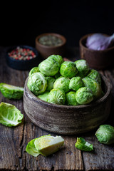 Fresh raw brussels sprout in bowl on wooden background