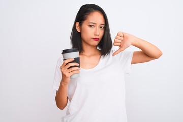 Young chinese woman drinking take away glass of coffee over isolated white background with angry...