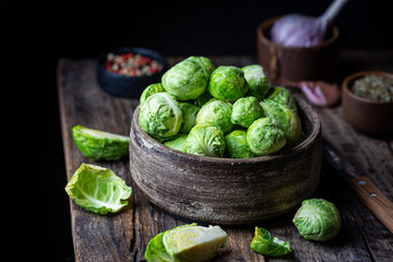 Fresh raw brussels sprout in bowl on wooden background