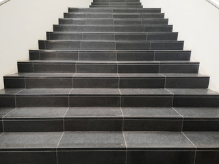 Fototapeta na wymiar Staircase with black marble stone stairs viewed in perspective. Abstract modern architecture or interior photo in minimalism style.