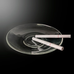 A cigarette in a saucer on a black table