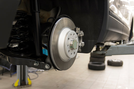 The car is lifted on a lift with the wheels removed in a car service. View of the rear suspension of the car. Brake system of the car.