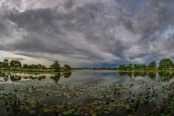 Fototapeta na wymiar Lake view evening of dark clouds moving in heavy raining above lotus lake, sunset with rain storm above Krajub reservoir, Ban Pong, Ratchaburi, Thailand.