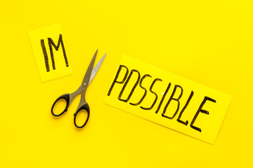 All is possible concept. Cut word impossible near scissors on yellow background