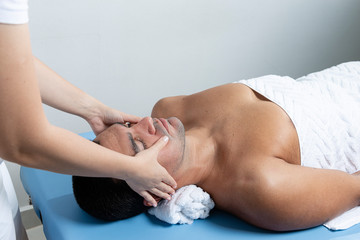 Obraz na płótnie Canvas Modern rehabilitation physiotherapy. Therapist massaging man's face.