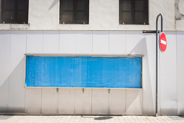 grand rectangle bleu sur une façade et un panneau sens interdit