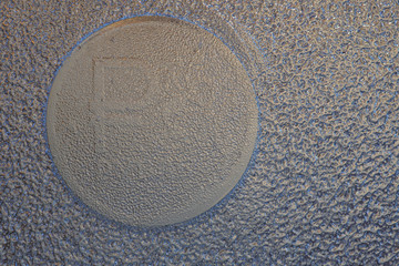 An imprint on the ice of a Russian coin of one ruble with the symbol of the national currency. Dark background or wallpaper. Blue and brown. Economics and finance of Russia. Reduced contrast. Macro