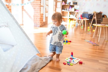 Adorable toddler playing around lots of toys at kindergarten