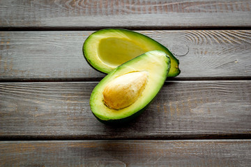 Avocado - ripe and bright, cutted in half - on dark wooden background closeup